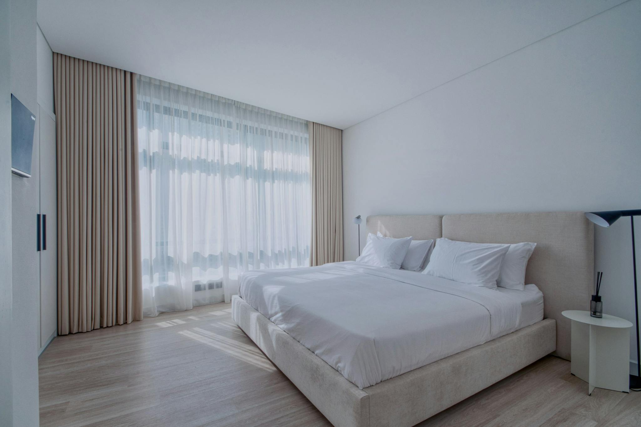 A serene and modern bedroom interior with elegant neutral tones and natural light.